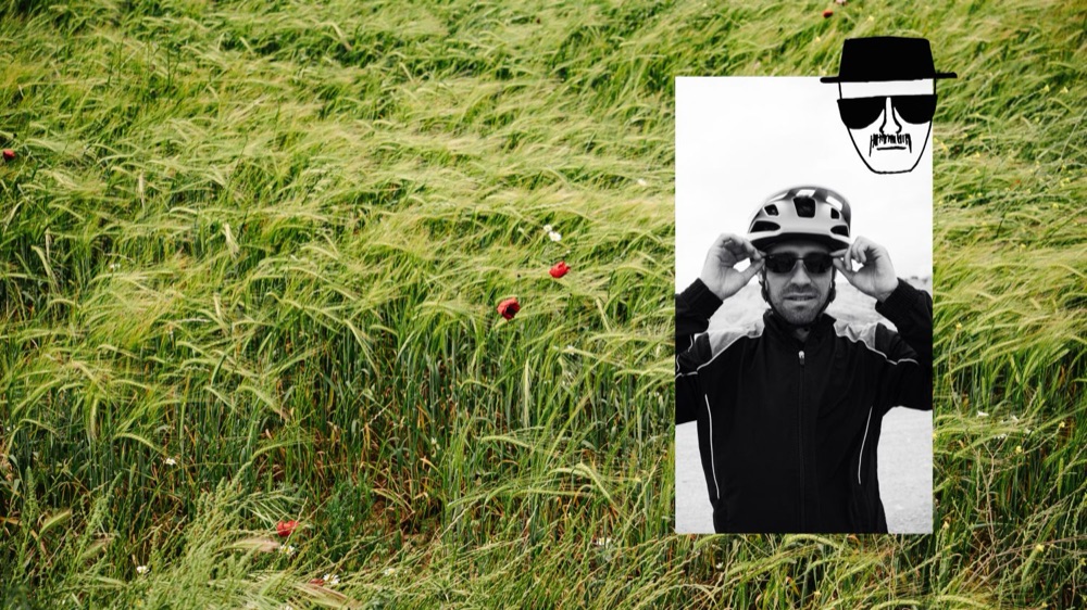 Ciclista con gafas de sol sobre un campo de cebada, con un dibujo de sombrero y gafas