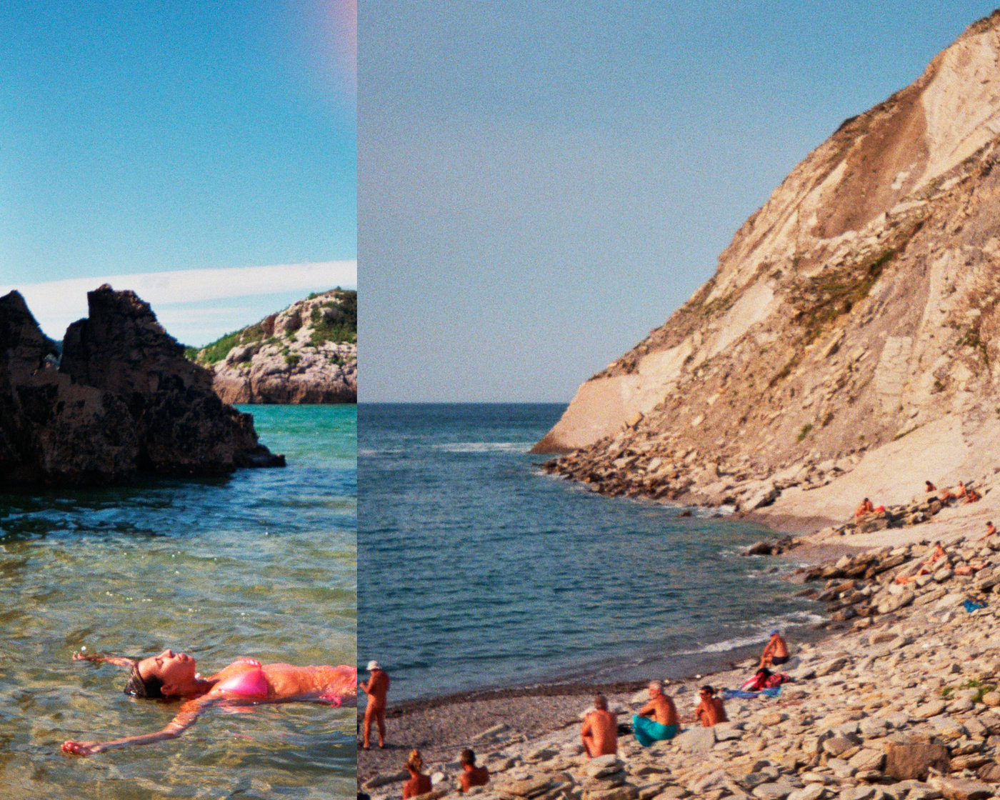 Bañista flotando y cala bajo un acantilado