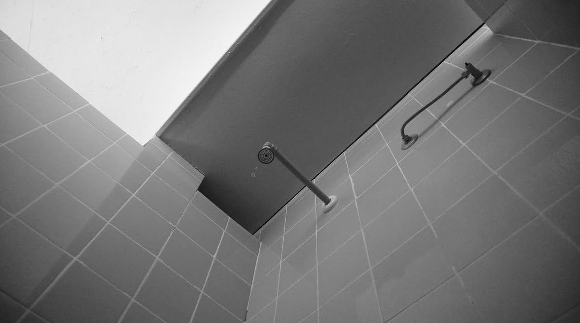 Techo de unas duchas alicatadas visto desde abajo, con una alcachofa
