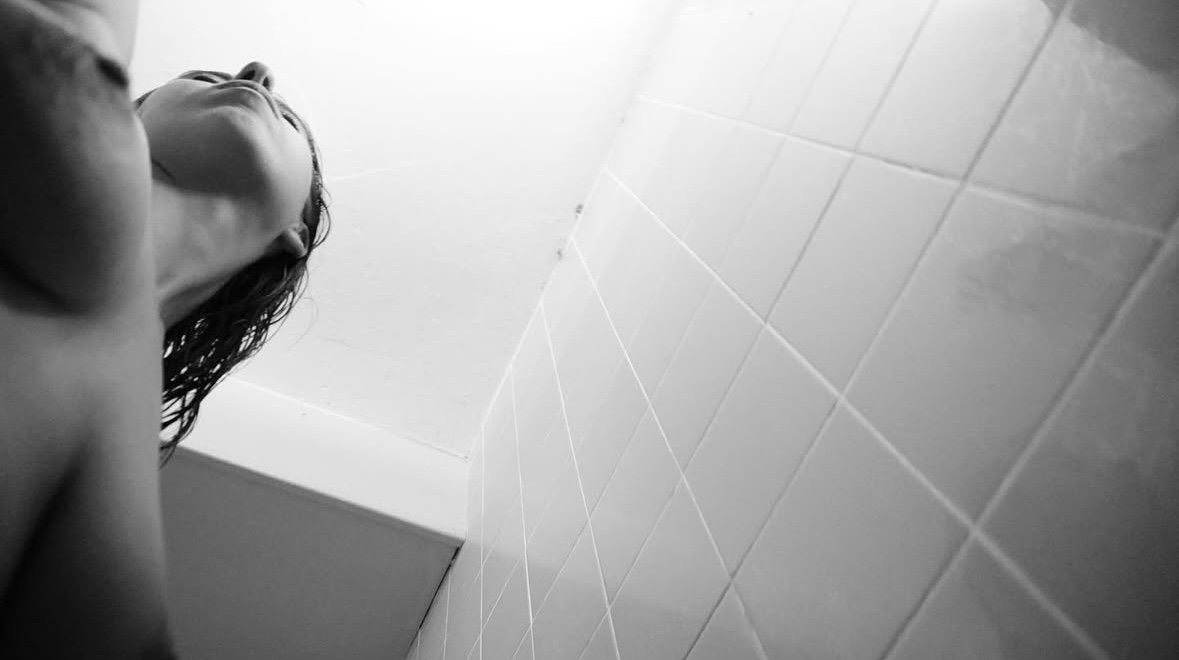 Mujer con el pelo mojado vista desde abajo en la ducha
