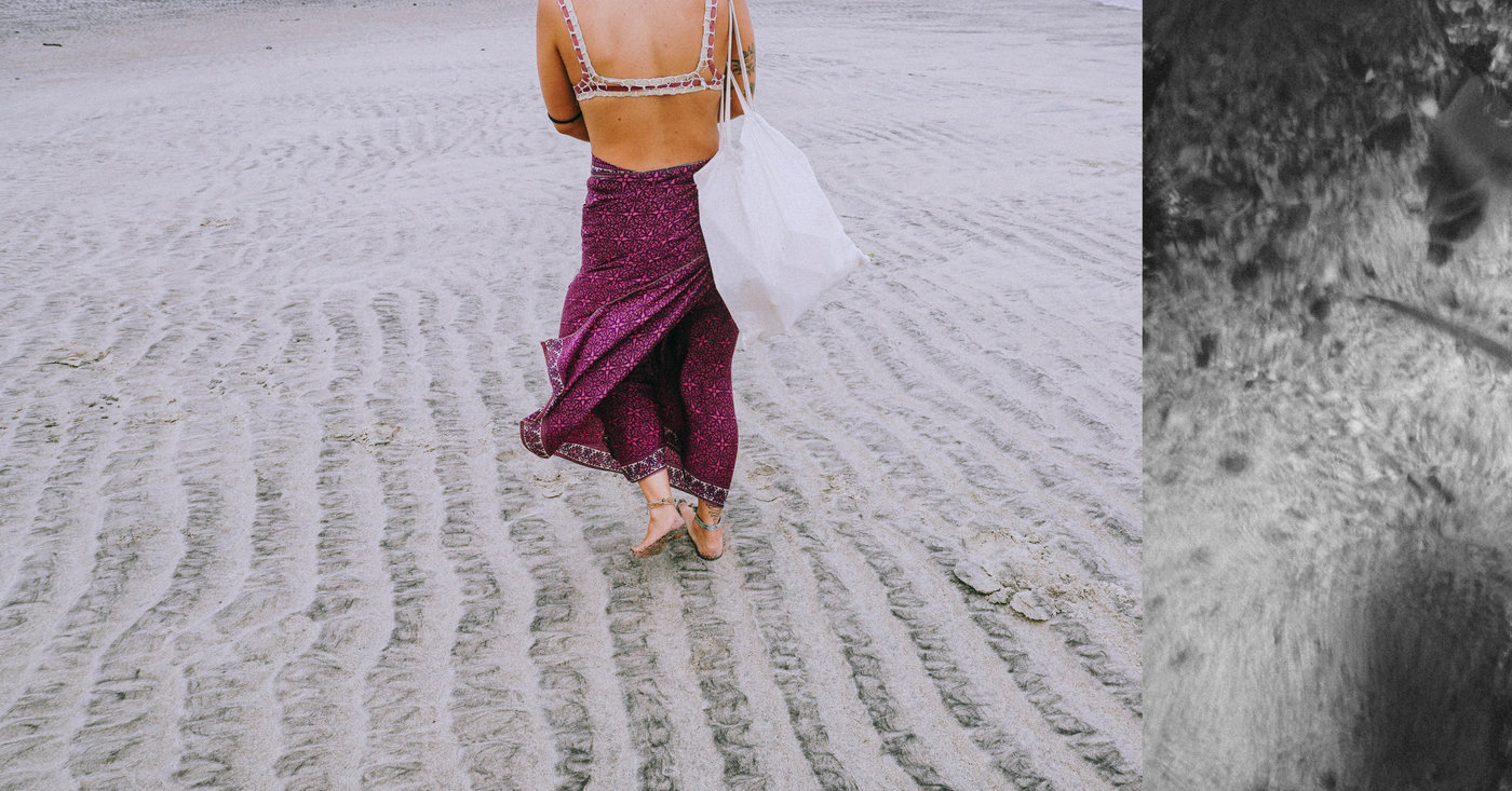 Mujer con pareo morado caminando por la arena