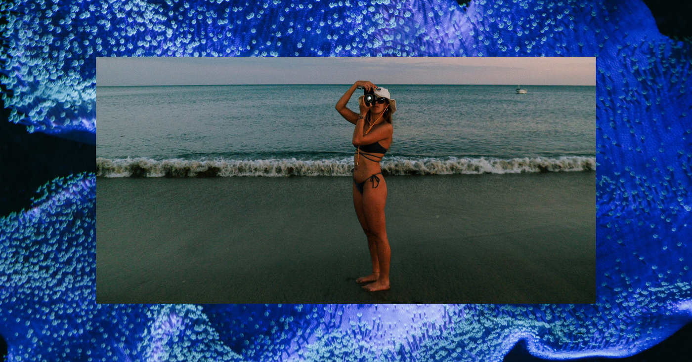 Mujer fotografiando en la orilla, enmarcada en azul