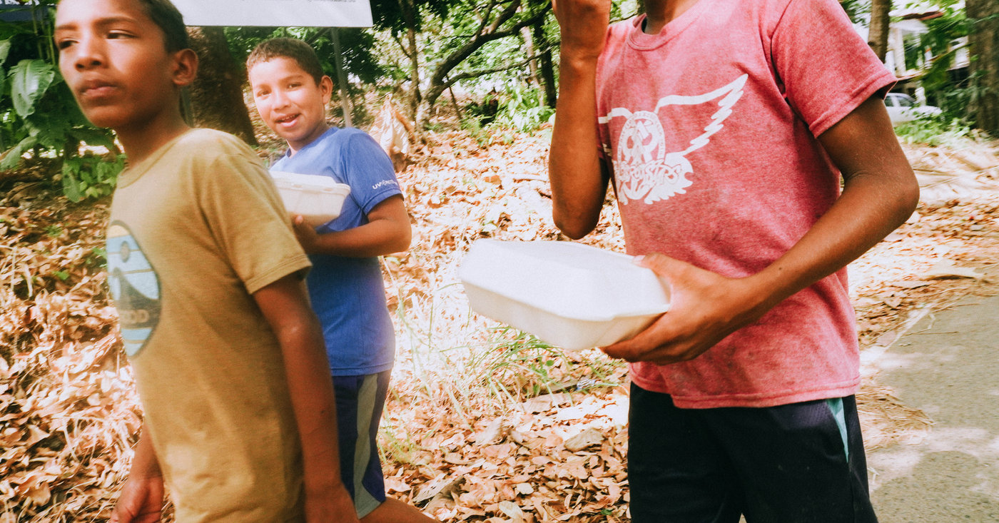 Niños caminando con fiambreras de comida